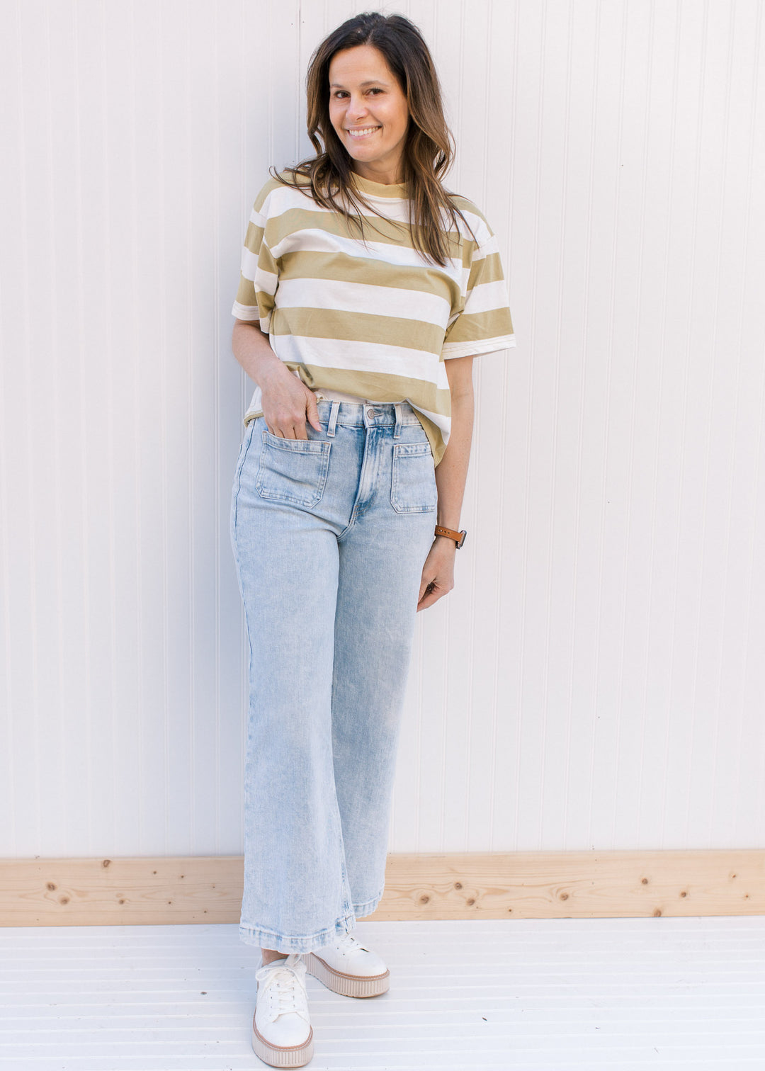Model wearing an avocado and cream striped top with a crew neck and short sleeves.