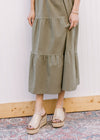 Close up of tiered skirt on an olive  midi with lined openwork crochet top and capped sleeves. 