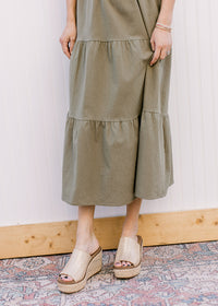 Close up of tiered skirt on an olive  midi with lined openwork crochet top and capped sleeves. 