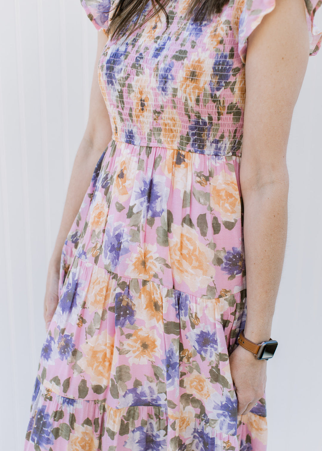 Close up of smocked bodice and tiers on a lilac dress with a floral pattern.