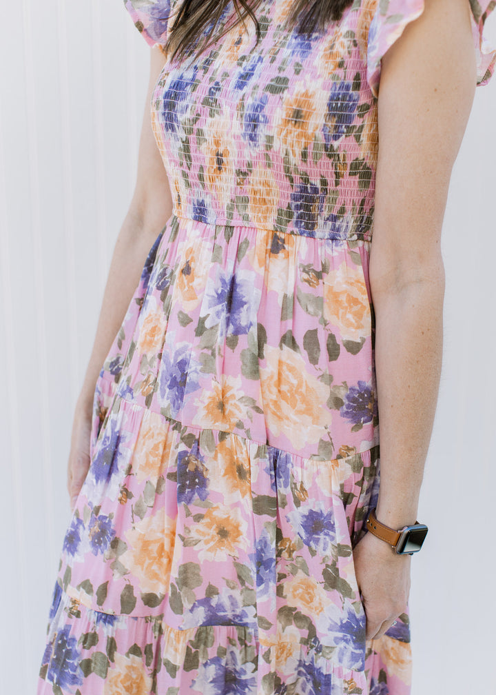 Close up of smocked bodice and tiers on a lilac dress with a floral pattern.