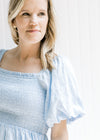 Close up view of a smocked bodice and short bubble sleeves on a model warning a baby blue dress.