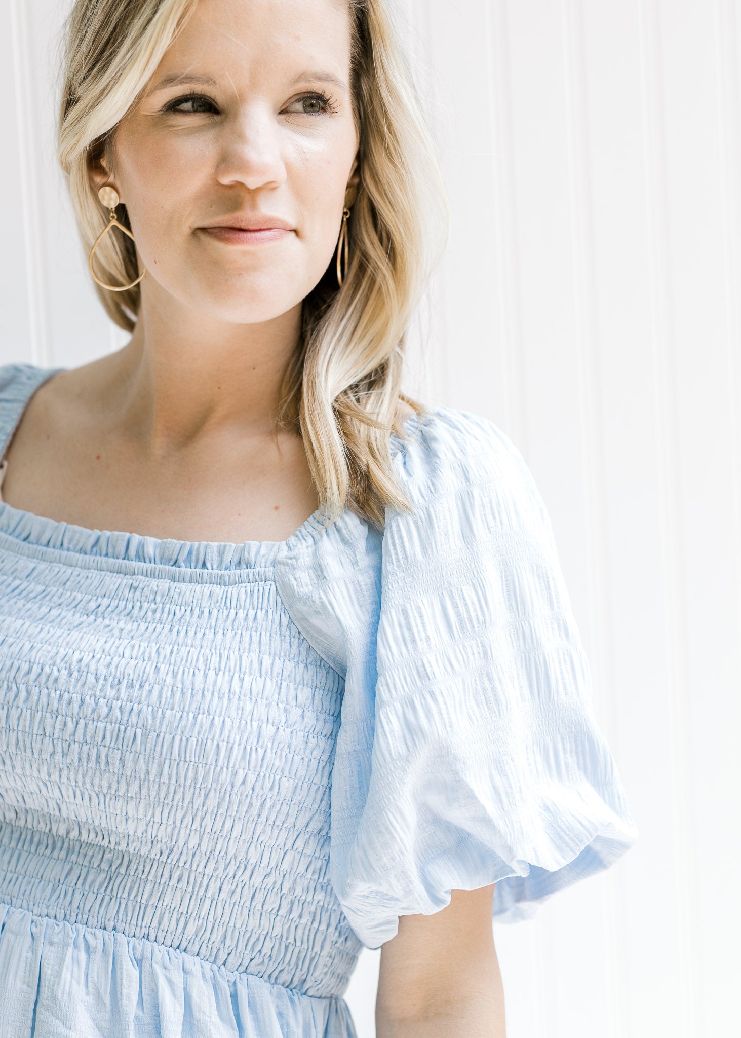 Close up view of a smocked bodice and short bubble sleeves on a model warning a baby blue dress.