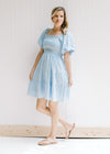 Model wearing a baby blue dress with a smocked bodice, square neckline and bubble short sleeves. 