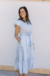 Model wearing a baby blue midi with short puff sleeves and elastic with a tie at the waist. 