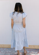 Back view of a tiered midi with puff short sleeves and a tie at the waist. 