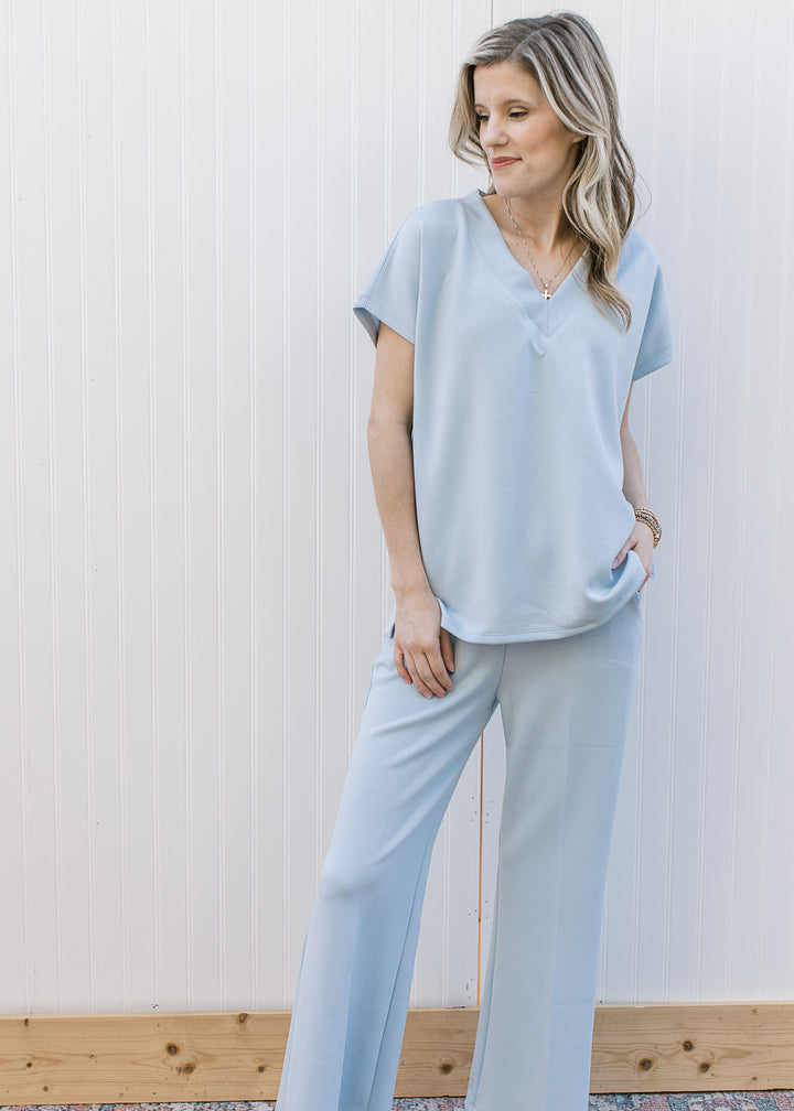 Model wearing a baby blue set the top has a v-neckline and short sleeves with wide leg bottoms.
