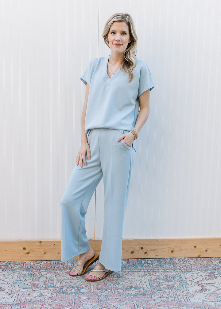 Model wearing sandals and a baby blue set with a v-neck, short sleeve top and wide leg bottoms.
