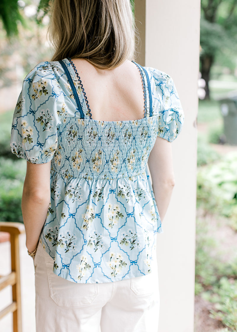 Back view of baby blue top with cream floral, smocked back, bubble short sleeves and square neck. 
