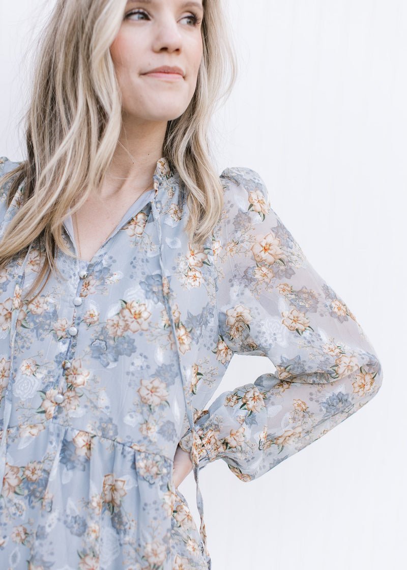 Close up of sheer sleeves and button front on a pale blue maxi with gold, cream and ivory floral.