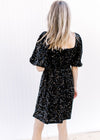 Back view of Model wearing an above the knee dress with black sequins, square neck and 3/4 sleeves.