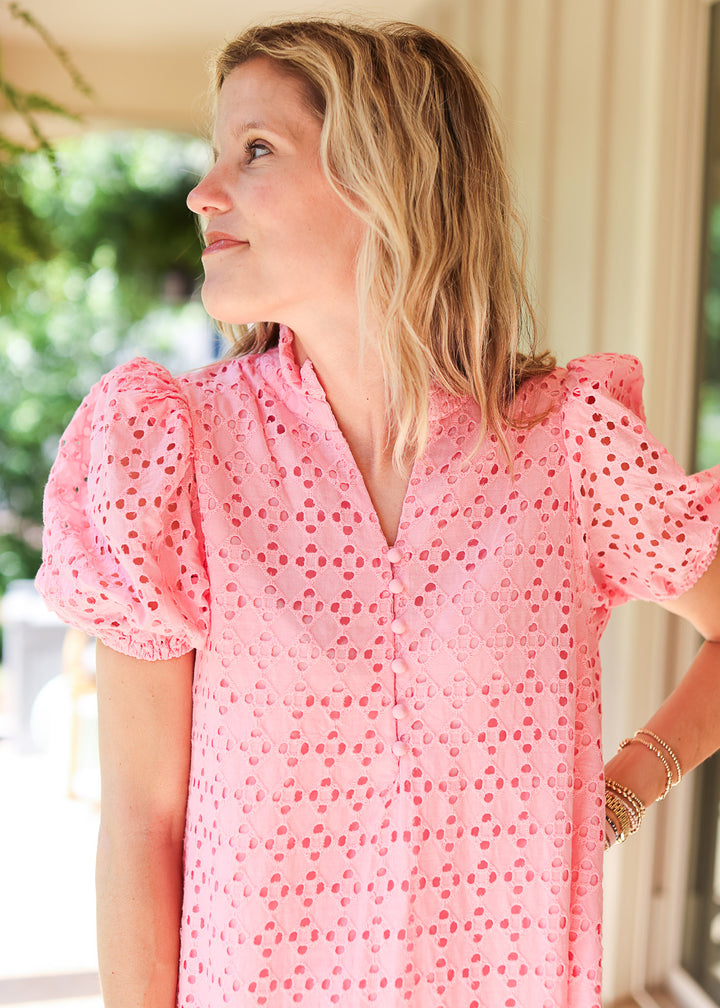 Close up of v-neck with buttons and short puff sleeves on a pink midi dress with eyelet detail. 