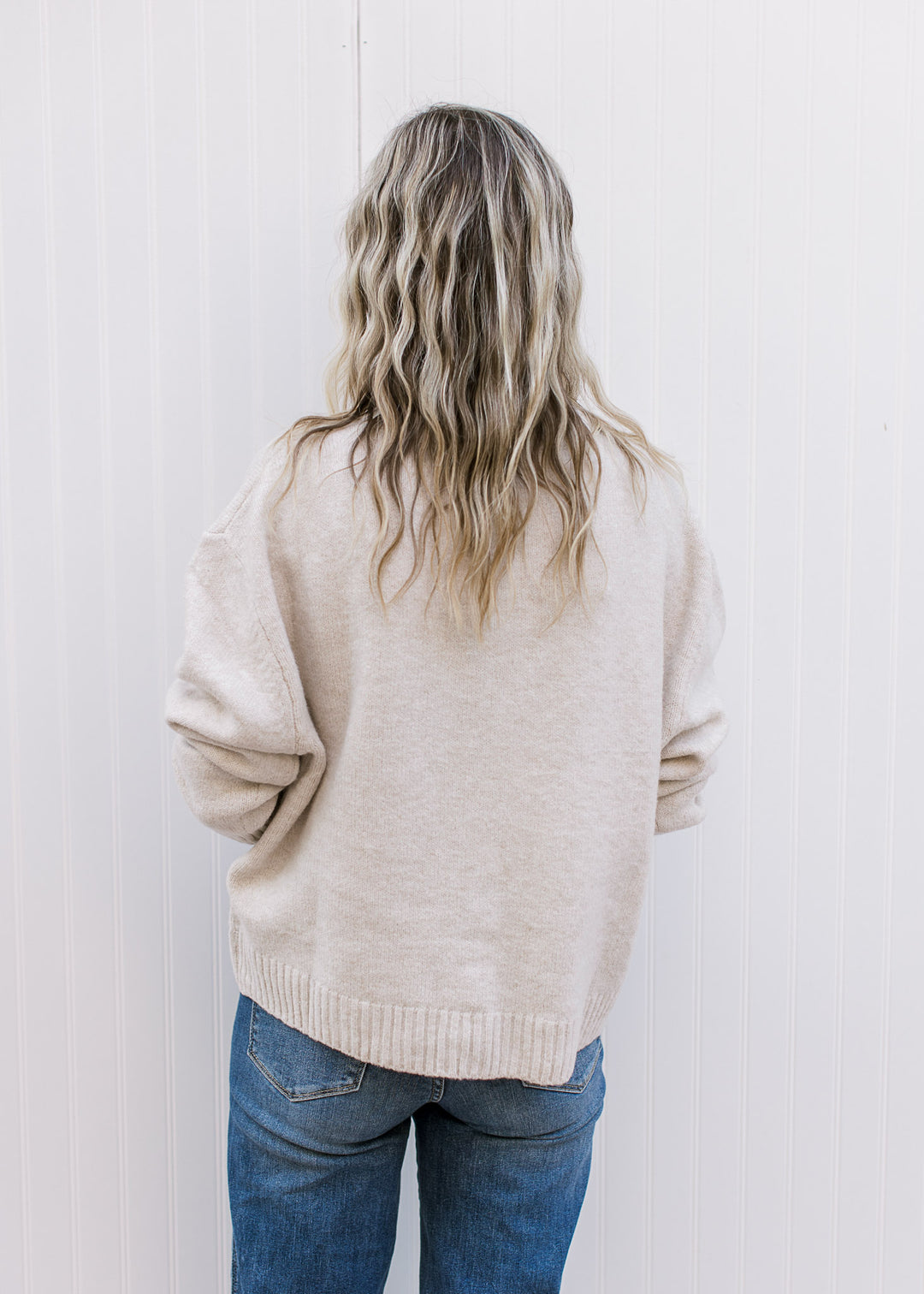 Back view of Model wearing a cream long sleeve cardigan with tone-on-tone 3D floral detail.