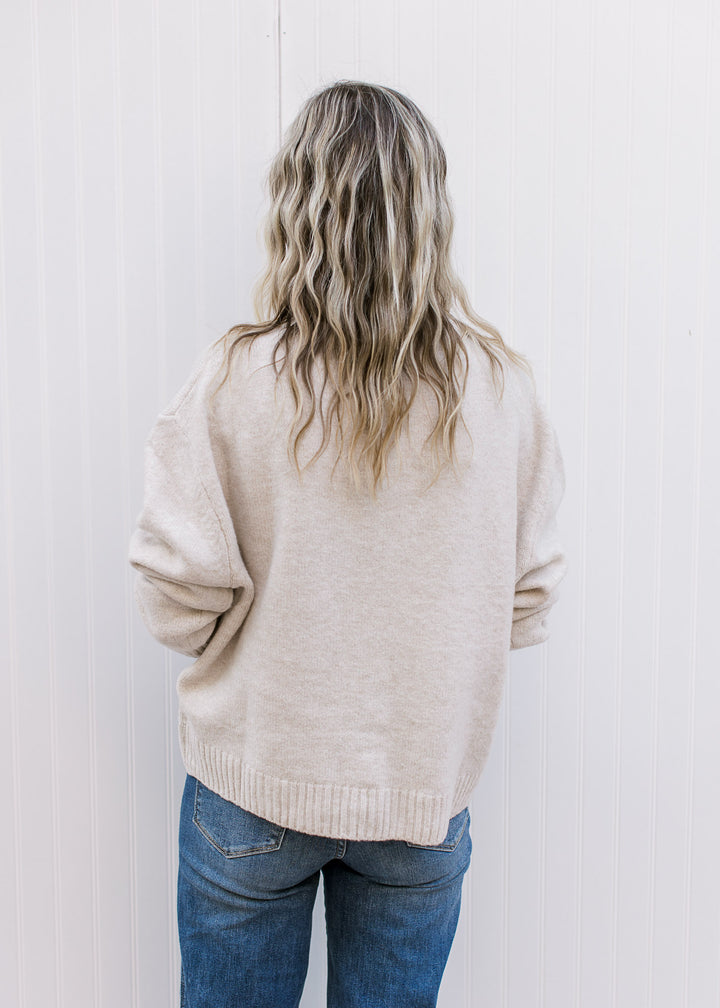 Back view of Model wearing a cream long sleeve cardigan with tone-on-tone 3D floral detail.