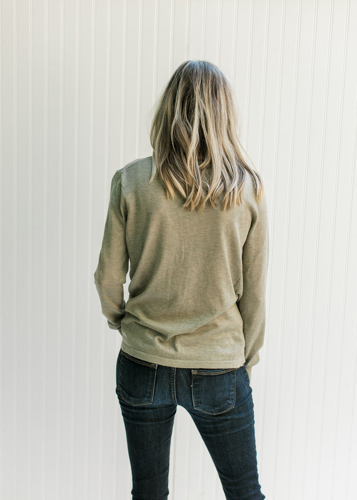 Back view of a Model wearing an olive long sleeve sweater with a round neck and a light material. 
