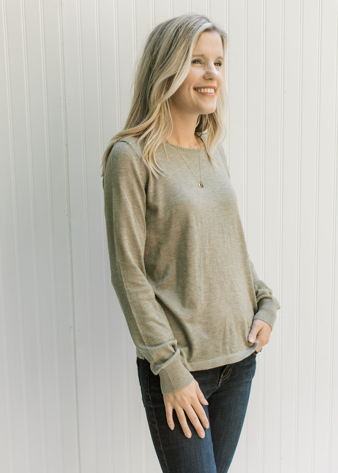 Model wearing jeans with an olive long sleeve sweater with a round neck and a lightweight material. 