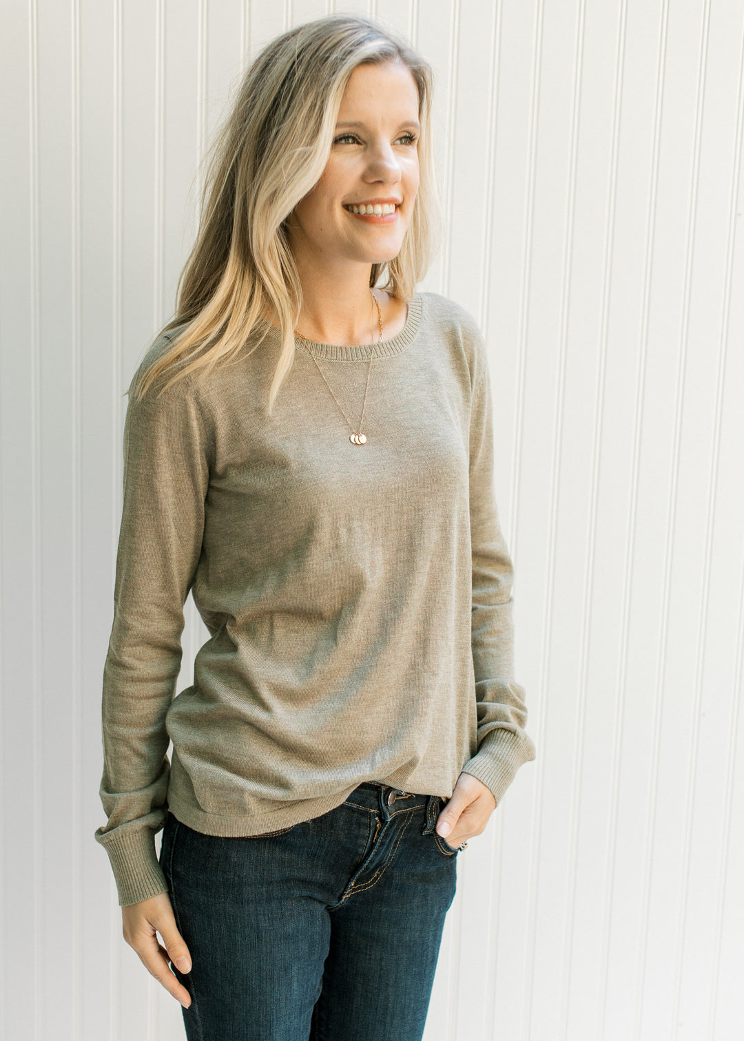 Model wearing an olive sweater with a round neck a lightweight material and long sleeves. 