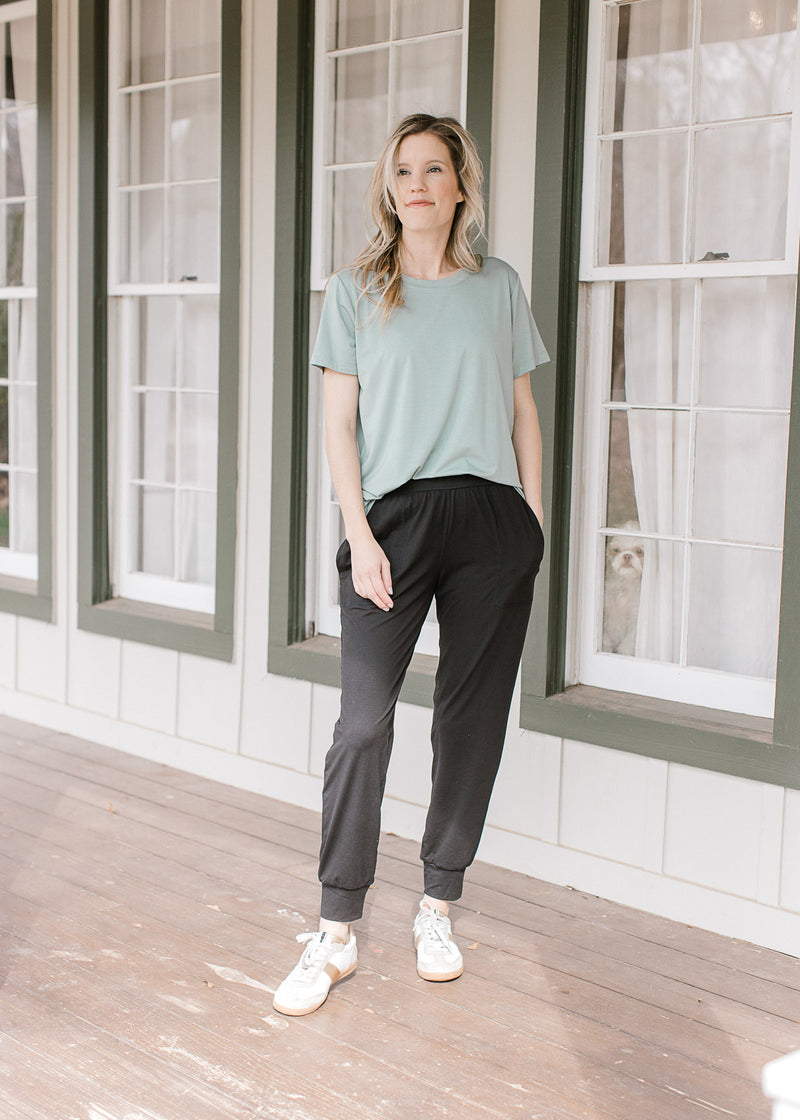 Model wearing a tee, sneakers and black joggers with patch front pockets and elastic waist.