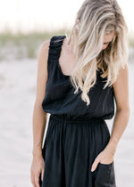 Close up view of elastic in waist and sleeves of a black jumpsuit. 