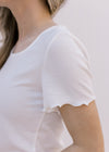 Close up of ruffle on short sleeve ivory top with ribbed material and a square neck.