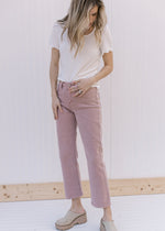 Model wearing mauve pants with a cream ribbed top with ruffled at hem and short sleeve.