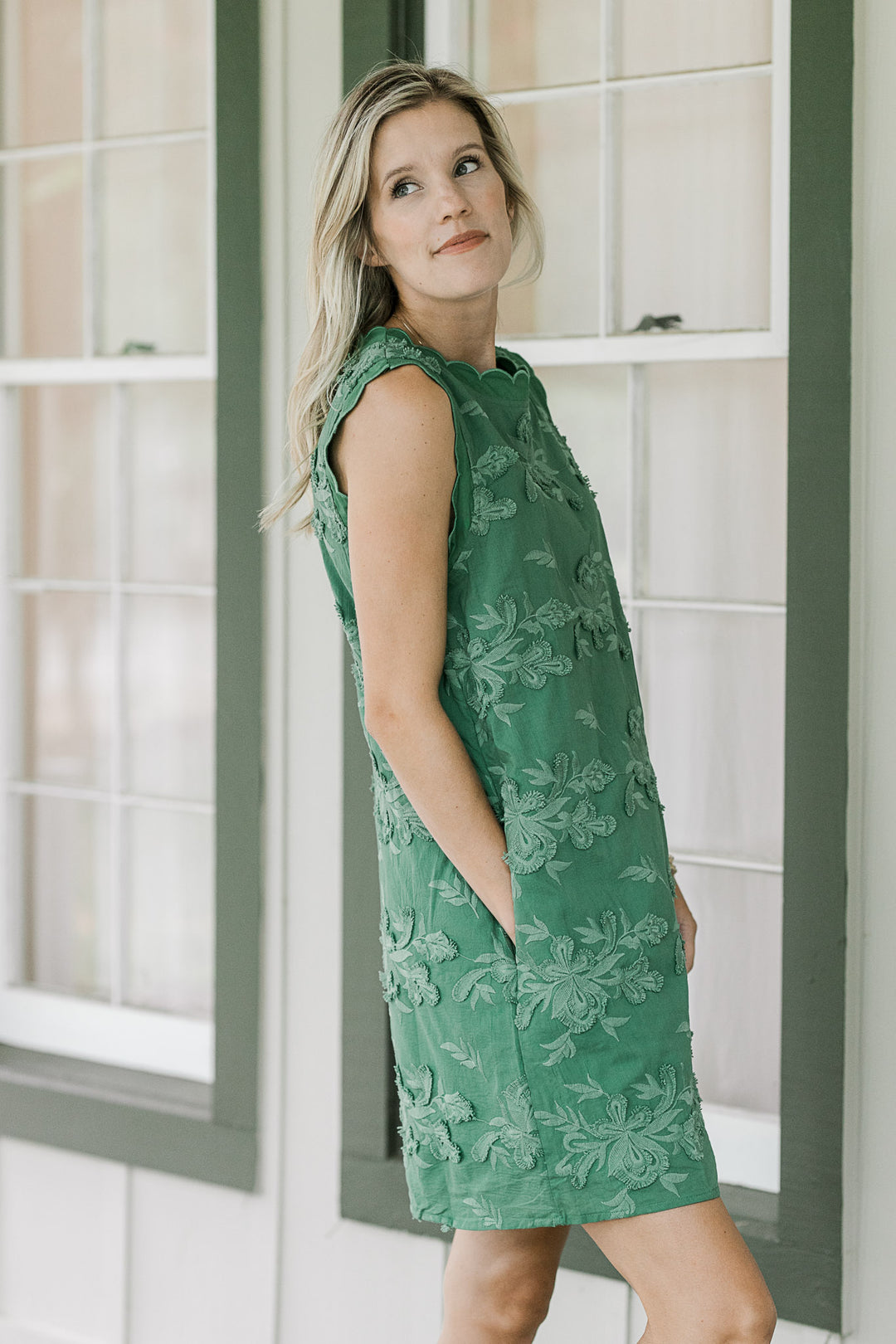 Model wearing a green tone on tone textured sleeveless dress with pockets. 