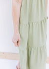 Close up of tiers on a v-neck basil green midi with ruffle cap sleeves. 