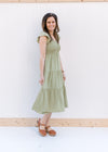 Model wearing a v-neck basil green midi with a smocked bodice and ruffle capped sleeves.