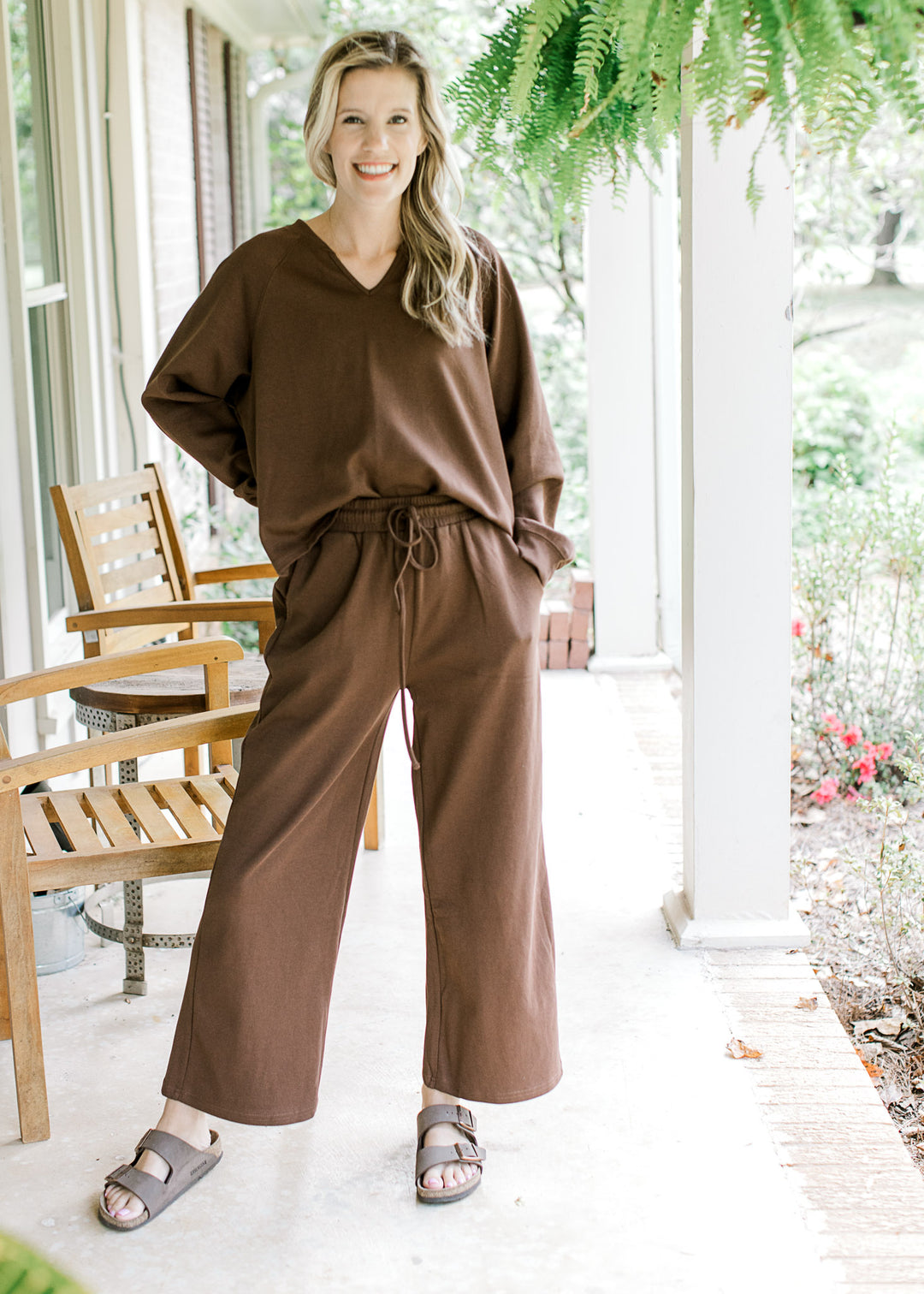 Model wearing a mocha colored set, top has long sleeves and v-neck with wide leg bottoms. 