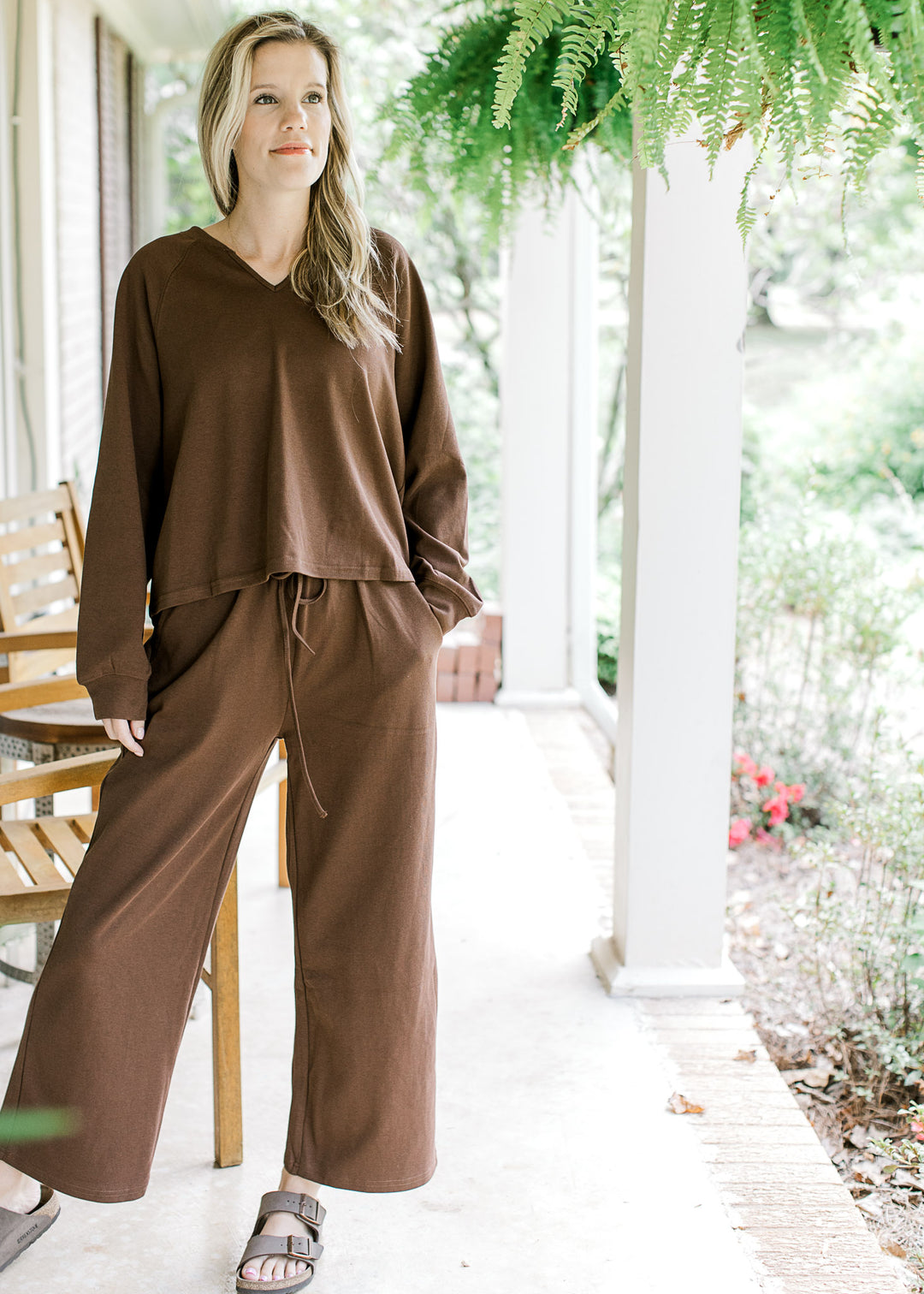 Model wearing a mocha set, top has long sleeves and v-neck with wide leg bottoms. 