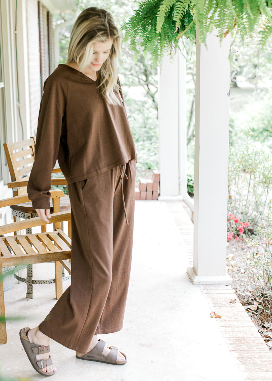 Model wearing sandals with a mocha colored set, top has long sleeves with wide leg bottoms. 