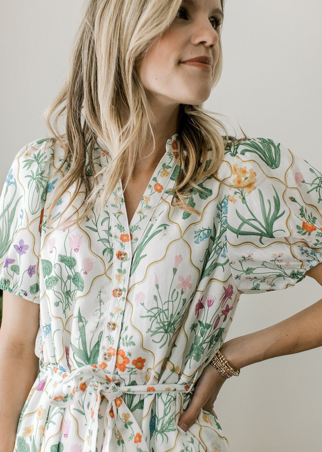 Close up of v-neck and tie waist on an off white midi with bright flare and bubble short sleeves. 