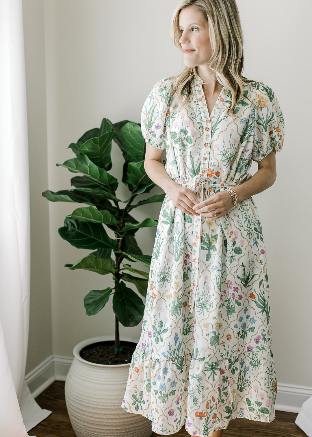 Model wearing an off white midi with bright floral, buttons, bubble short sleeves and pockets. 
