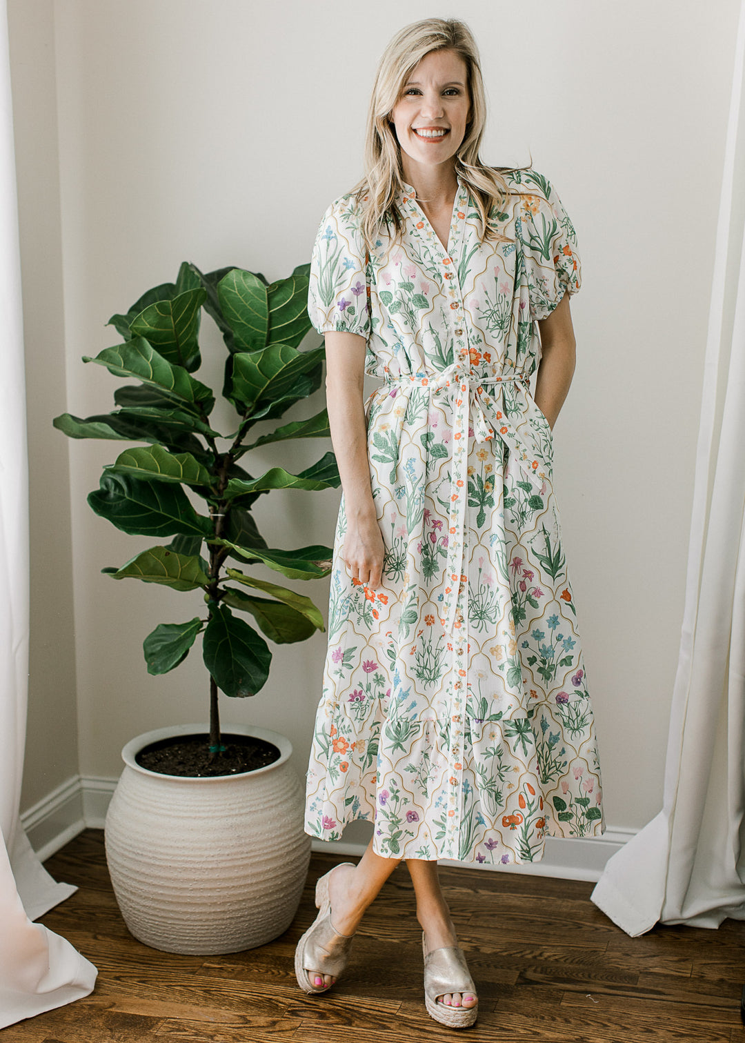 Model wearing an off white midi with bright floral, adjustable tie, short sleeves and pockets. 