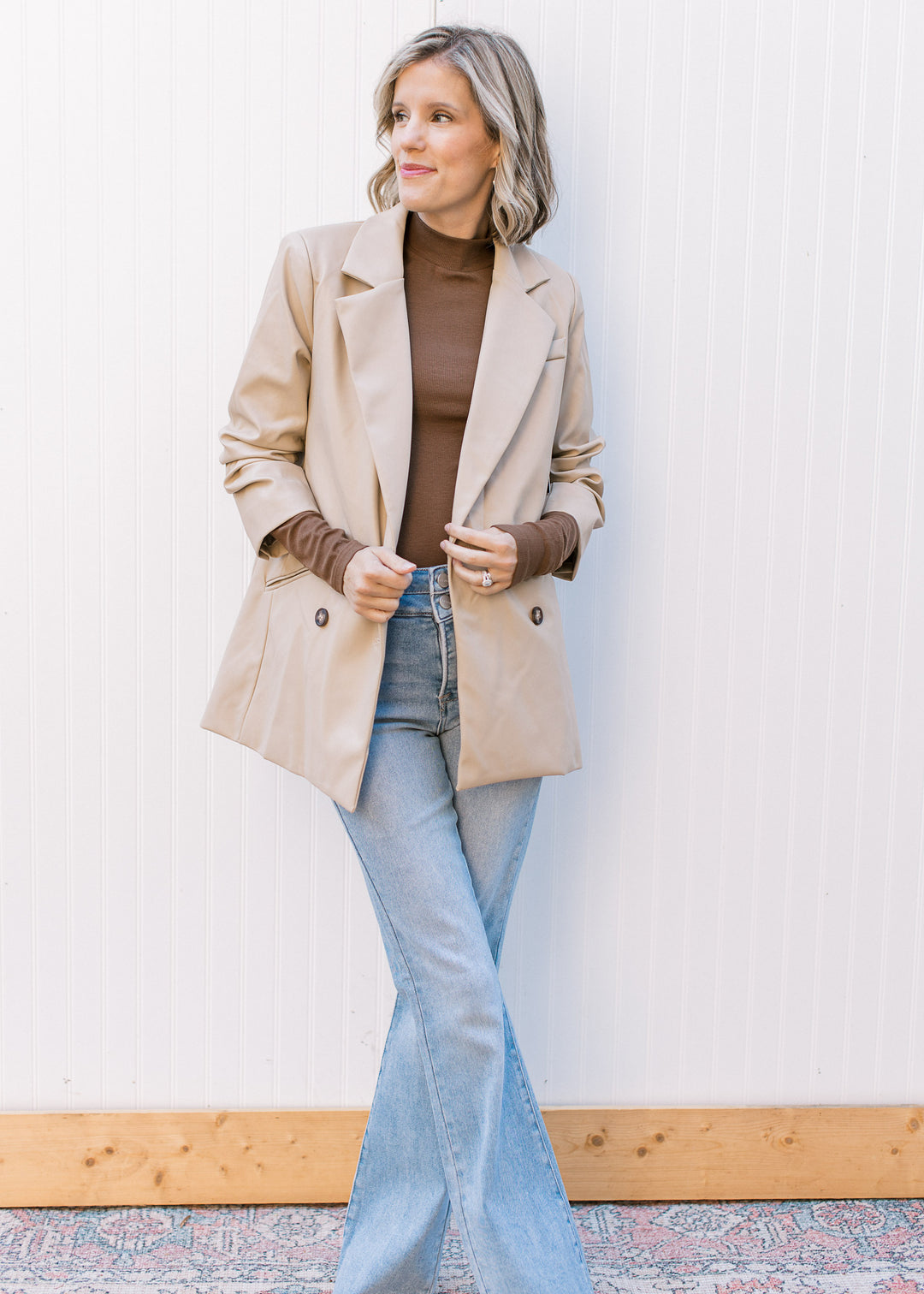 Model wearing a beige, faux leather jacket with double-button closure, flap collar and 3/4 sleeves.