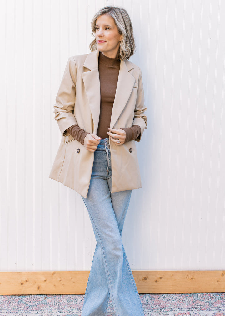 Model wearing a beige, faux leather jacket with double-button closure, flap collar and 3/4 sleeves.