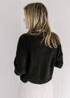 Back view of Model wearing a soft black sweater with a round neck and long sleeves.