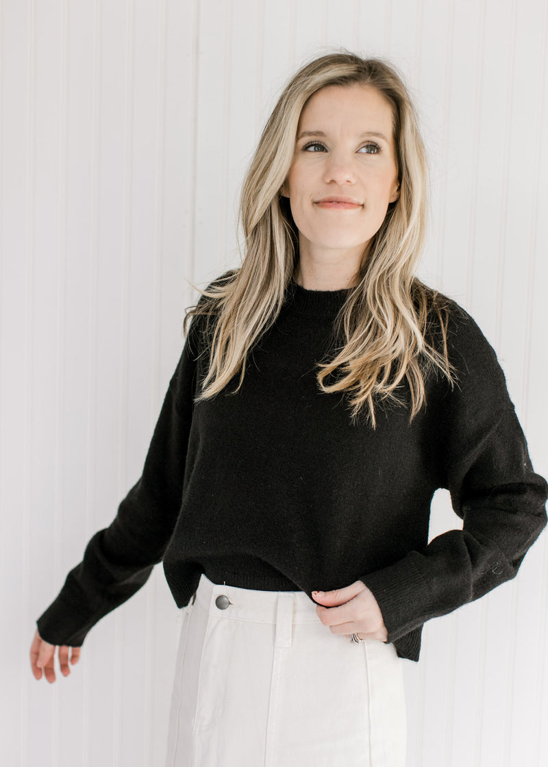 Model wearing a soft black sweater with a round neck and long sleeves.