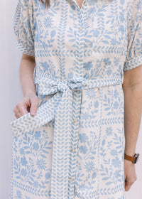 Close up of tie belt at the waist of a cream midi with pale blue floral and a button front. 