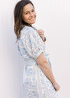 Side view of Model wearing a cream midi with pale blue floral, bubble short sleeves and tie belt.