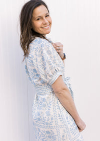 Side view of Model wearing a cream midi with pale blue floral, bubble short sleeves and tie belt.