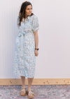 Model wearing sandals and a button front cream midi with pale blue floral and bubble short sleeves.