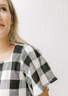 Close up view of short sleeves on a black and cream large scale gingham top. 
