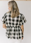 Back view of Model wearing a black and cream top with large gingham, a square neck and short sleeve.