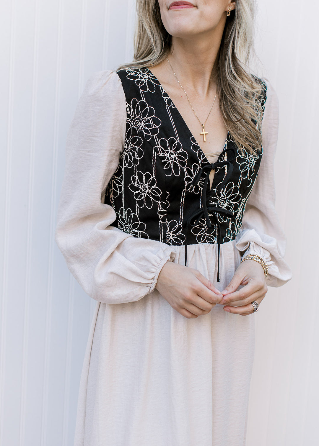 Close up of ivory stitching on the black bodice of an ivory midi with v-neck and long poet sleeves.