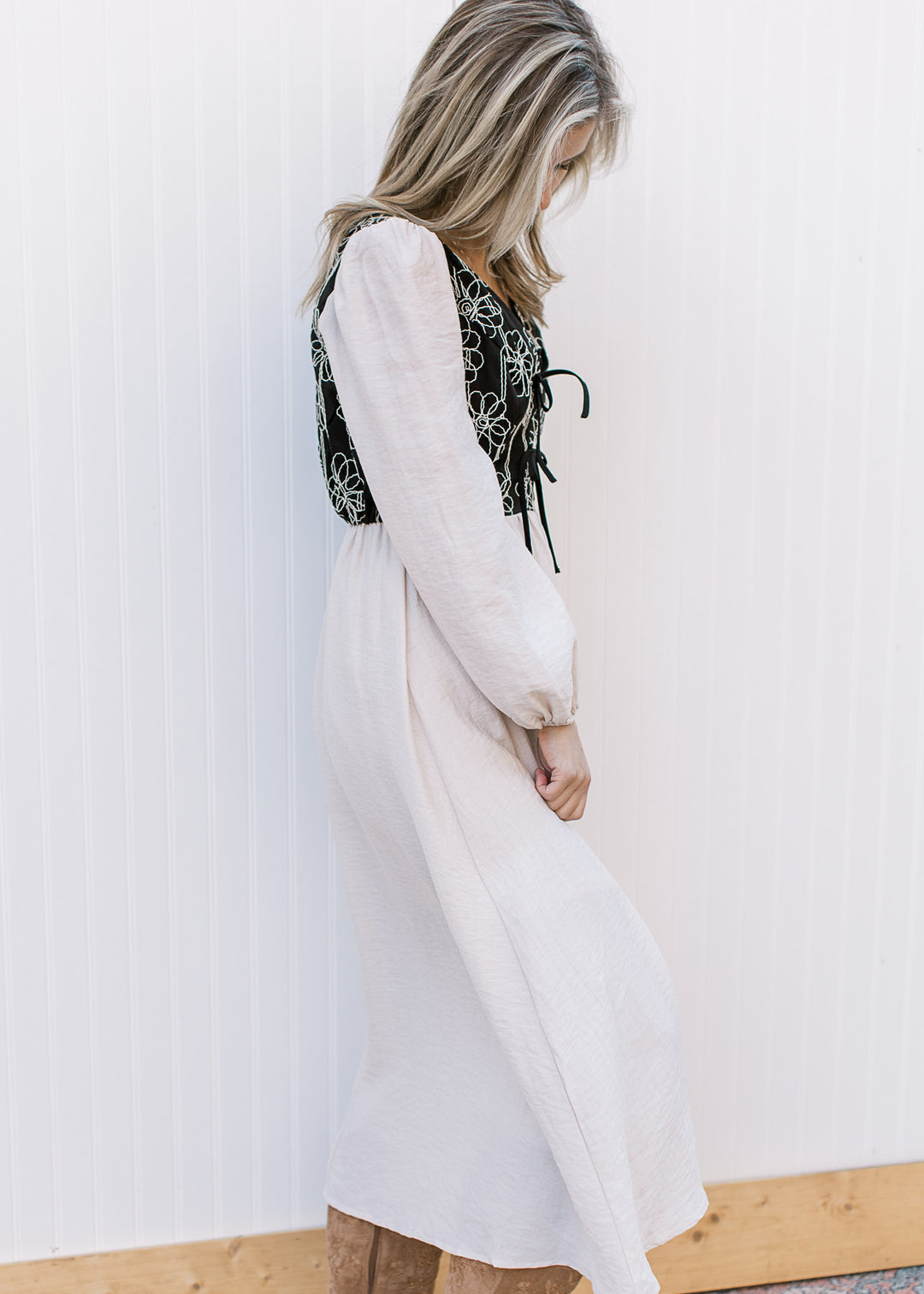 Side view of Model wearing an ivory midi with a black bodice v-neck and long sleeves.