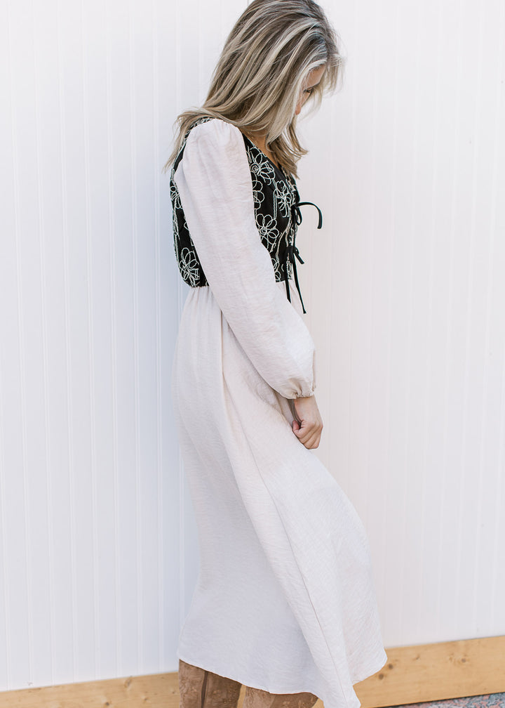 Side view of Model wearing an ivory midi with a black bodice v-neck and long sleeves.