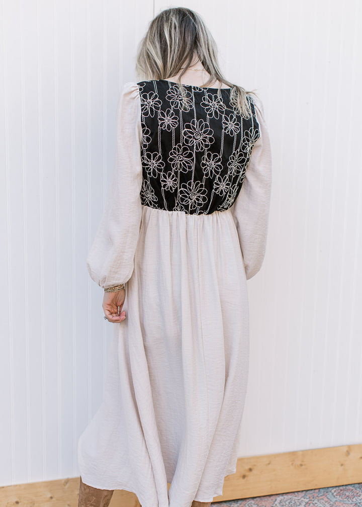 Back view of Model wearing an ivory midi with a black bodice with ivory floral and elastic waist. 