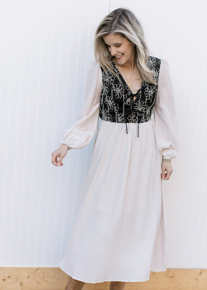 Model wearing an ivory midi with a black bodice adorned with  ivory floral and an elastic waist.