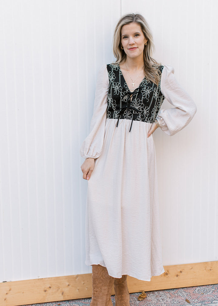 Model wearing boots and an ivory midi with a black bodice with ivory floral and long sleeves.